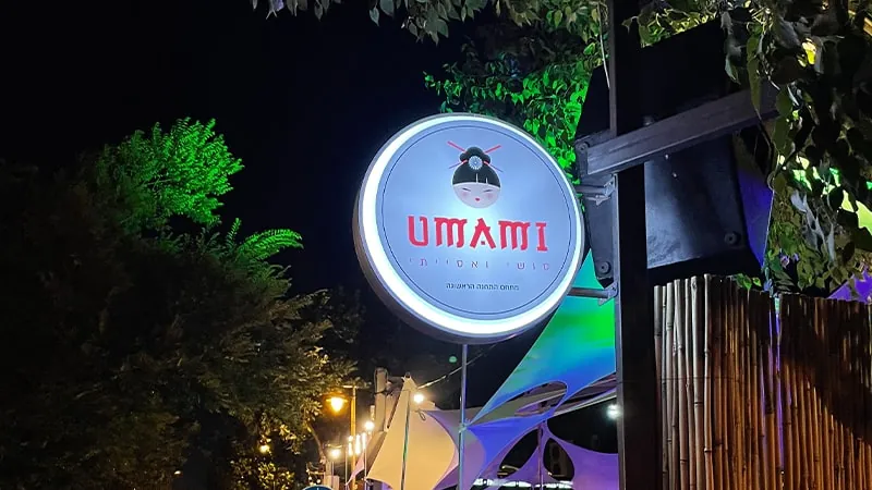 שלט דגל עגול מואר של UMAMI בלילה